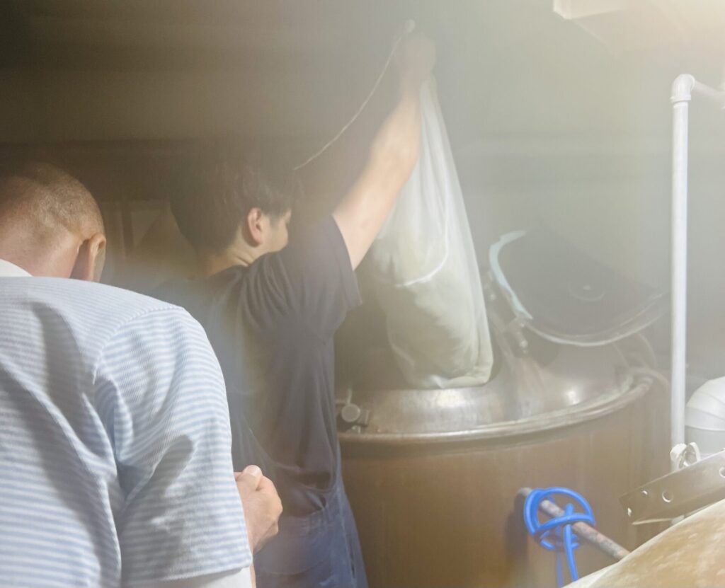 高温の中ホップを投入する作業を行うブルワーの加藤さん